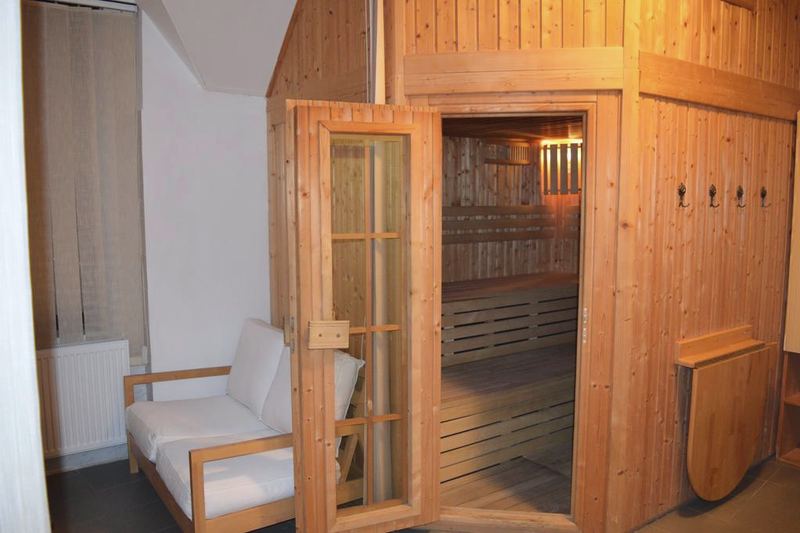 Fínska sauna s otvorenými presklenými dverami a osvetlenými lavicami.