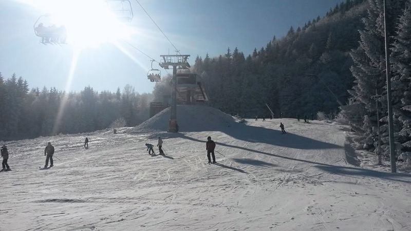 Lyžiari na svahu SKI Králiky, sedačková lanovka v nízkom slnku.